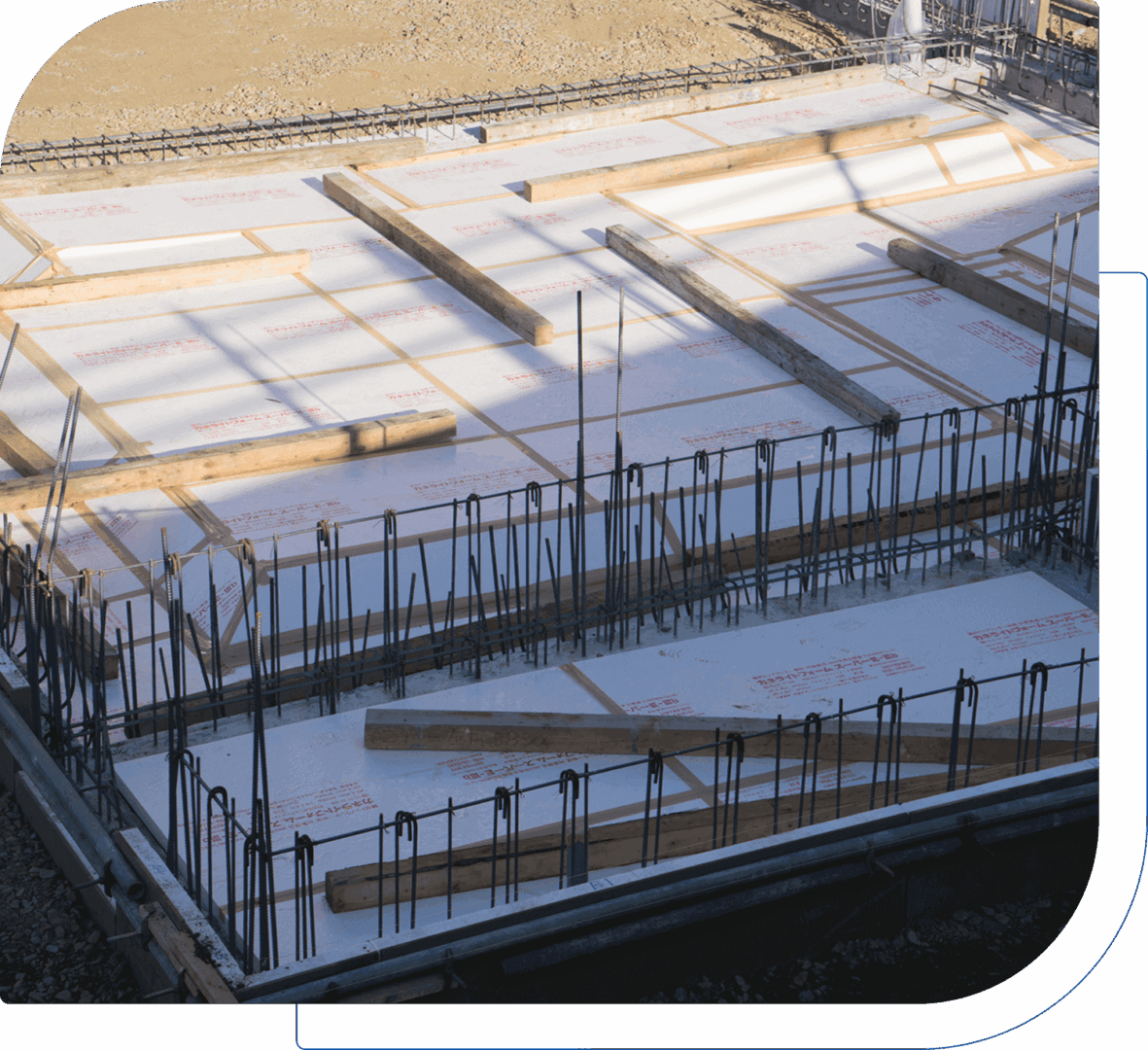 Concrete foundation with steel reinforcements at a construction site.