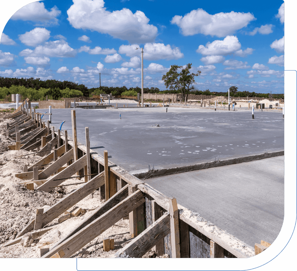 Freshly poured concrete slab at a construction site on a clear day.
