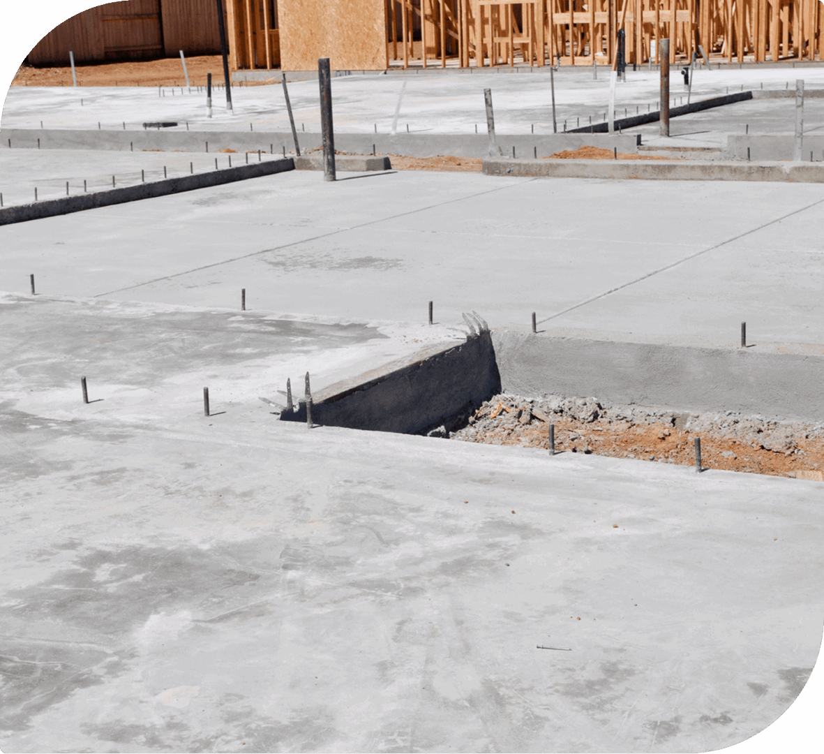 Concrete slab foundation with plumbing pipes and wooden framing in progress.