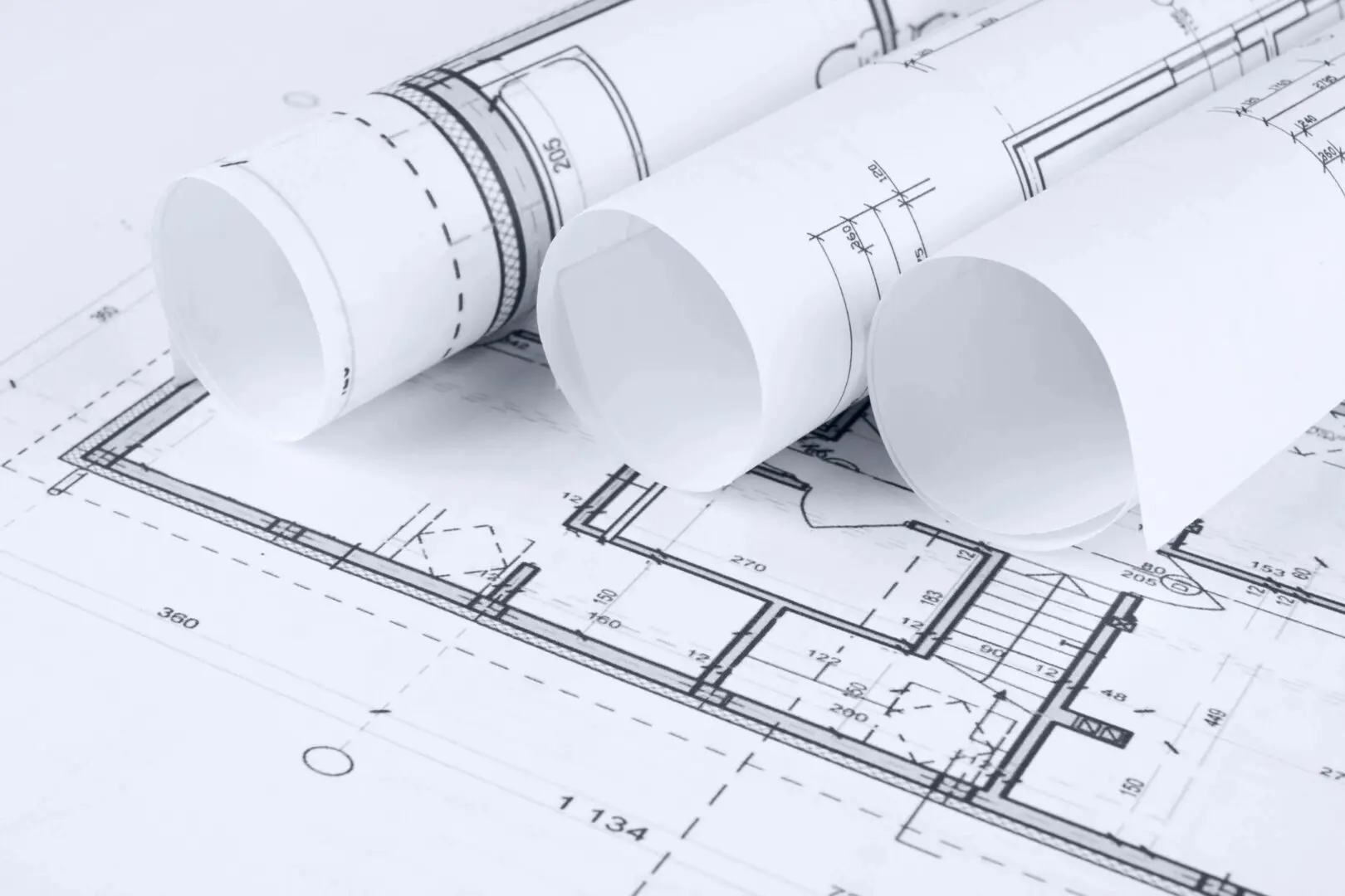 Rolled architectural blueprints and floor plans on a surface.